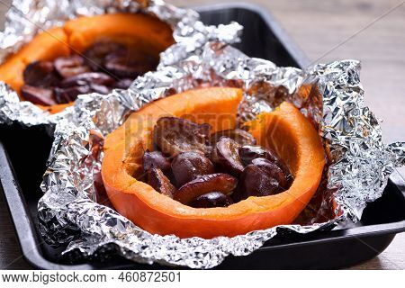 Hokkaido Pumpkin Halves Baked In Foil Stuffed With Plums On A Baking Sheet. Vegetarian Food. The Ket