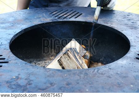 Ignition With A Burner. A Man Sets Fire To Firewood With A Gas Burner. Breeding A Fire. Barbecue Par