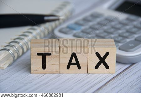 Tax Word On Wooden Blocks With Calculator, Notebook And Pen Background. Tax Concept