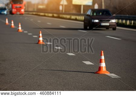 A Row Of Traffic Orange Striped Cones On The Road. Sunlight. These Objects Are Temporary Traffic Con