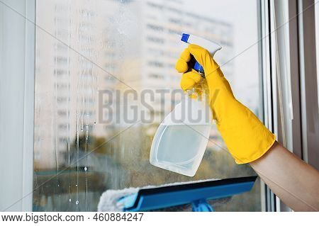 Man In Yellow Gloves Cleaning Window With Squeegee And Spray Detergent At Home Terrace. House Cleani