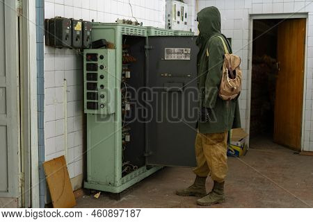 Young Survivor Man Looks At The Switchboard. Wandering Stalker. Post Apocalypse. Traveling On A Post