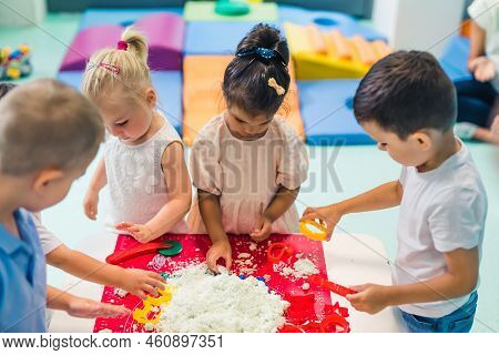 Fun Sensory Play With Moldable And Fluffy Kinetic Sand At Nursery School. Toddlers Standing Around T
