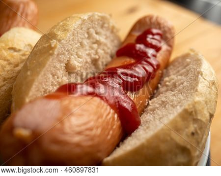 Boiled Sausage With A Bun On A Wooden Background.