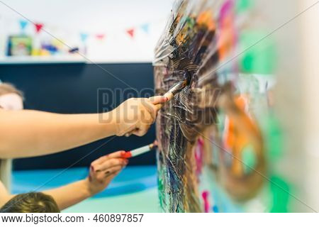 Close Up Toddlers Hands. Cling Film Painting. Children Painting With Brushes And Paints On A Cling F