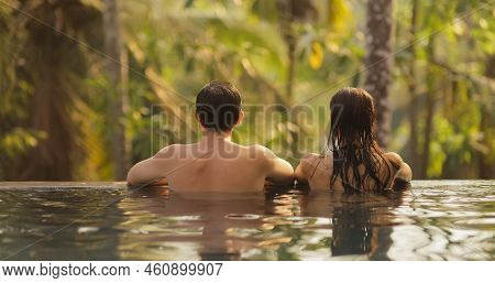 Panoramic Photo Of Young Adult Couple In Love Swimming Together In Open-air Infinity Pool Enjoying T