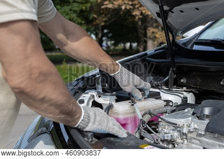 Man Opens Cap Of Expansion Tank In Car. Hand Opens Cap Of Car Coolant Expansion Tank
