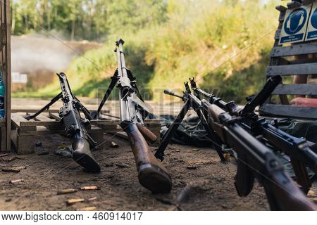Various Rifles Laying On Ground Of Firing Range. Military Equipment Storage. Ammunition And Weaponry