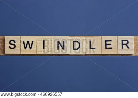 Gray Word Swindler From Small Wooden Letters On A Black Table