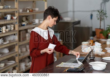 Young Female Entrepreneur Looking At Bills, Tracking Expenses, Craftswoman Potter Studio Owner Doing