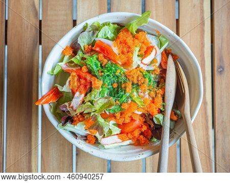 Japanese Salad (kanikana And Ebiko) In A Bowl With Bamboo Cutlery Placed On A Wooden Table. Close-up