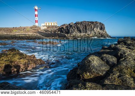 Beautiful Scenic Landscape With Classic Lighthouse On The Coast And Blue Ocen And Sky In Background 