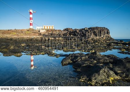 Beautiful Scenic Landscape With Classic Lighthouse On The Coast And Blue Ocen And Sky In Background 