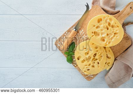 Cheese Maasdam Or Radamer. Piece Of Cheese On Wooden Stand Board On White Wooden Table Background. T