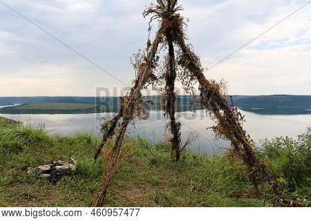 A Smooth Calm Water View. A Tent Made Of Twigs On The Banks Of A Large River.
