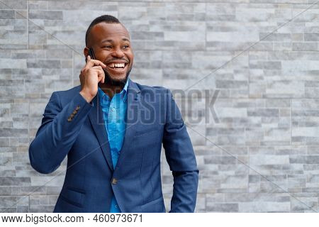 Portrait Of Confident African American Male Professional Wearing Blue Suit Using Smartphone While St