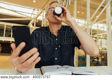 Caucasian Serious Mature Male Executive Discussing On Video Conference Over Mobile Phone In Corporat