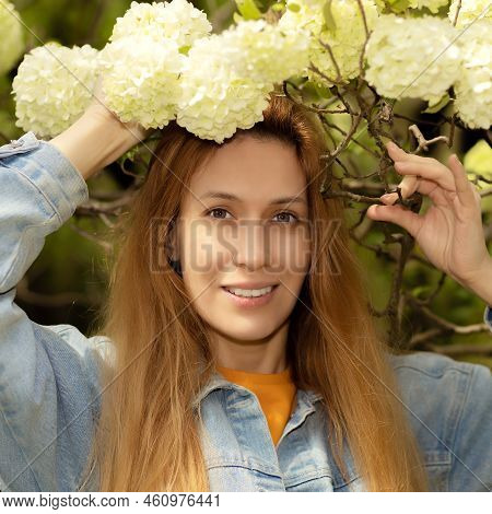 A Woman In Viburnum Buldenezh Flowers. Viburnum Buldenezh. Smiling Woman In Buldenezh Flowers. Selec