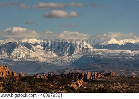Snow Covered La Sal Mountains Loom Over Firey Furnace In Arches National Park