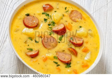 Close-up Of Kartoffelsuppe, German Creamy Potato Soup With Sausages In White Bowl On White Wooden Ta