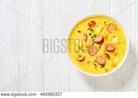 Kartoffelsuppe, German Potato Soup With Sausages In White Bowl On White Wooden Table, Horizontal Vie