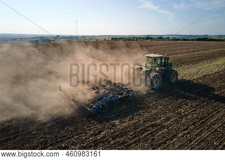 Aerial View Of Tractor Plowing Agriculural Farm Field Preparing Soil For Seeding In Summer.