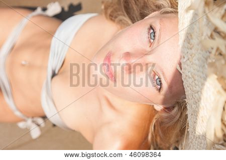 美丽的年轻 bolonde 女人的带草帽的比基尼在海滩上