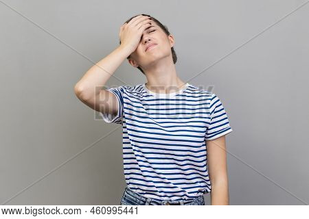 Portrait Of Upset Frustrated Woman Wearing Striped T-shirt Holding Forehead With Hand, Making Facepa