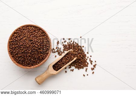 Scoop And Bowl With Buckwheat Tea Granules On White Wooden Table, Flat Lay
