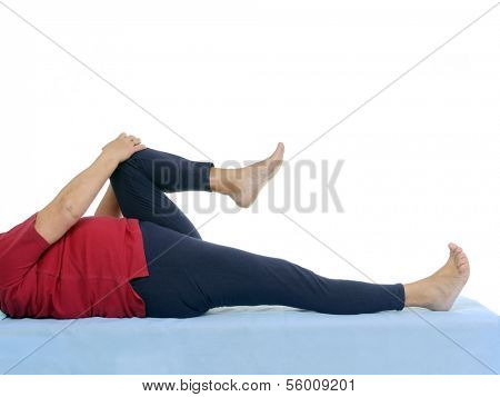 Older patient performing funtional test of hip joint contraction lying on bed