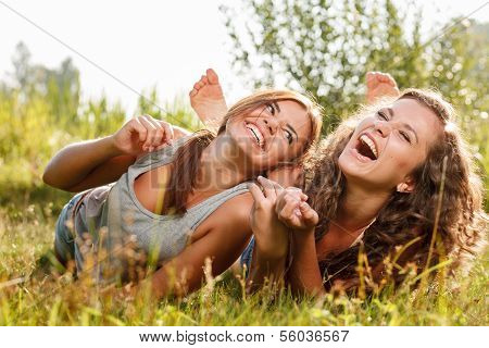 Two Girlfriends Lying Down On Grass