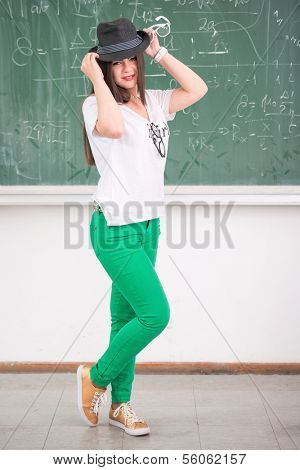 Cute schoolgirl with hat standing in schoolroom