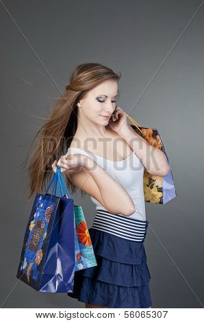 Young smiling woman with shopping bags over grey background