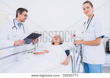 Portrait of two doctors visiting a female patient in the hospital