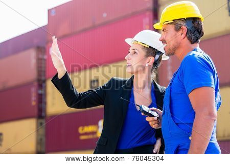 Freight shipping at container terminal of port, worker and manager discussing shipments