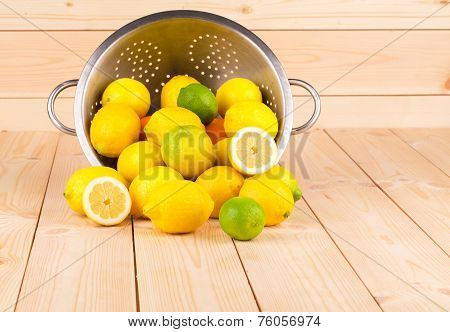 Composition of metal colander and lemons.