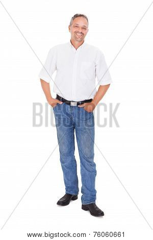 Smiling mature man standing with hands in pockets