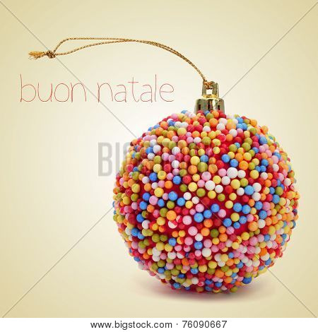 a christmas ball coated with nonpareils of different colors and the sentence buon natale, merry christmas written in italian, on a beige background