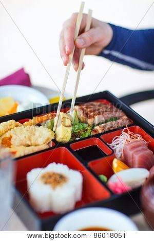 Delicious Japanese lunch bento box with rice, fish sashimi, omelet, meat and vegetables