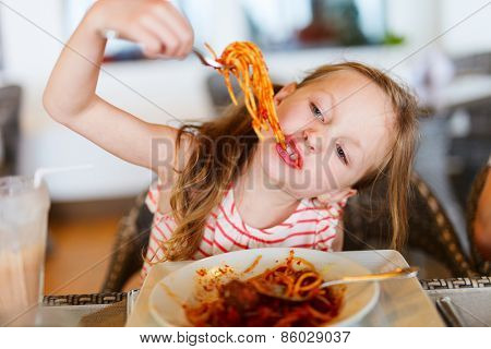Portrait of adorable little girl eating spaghetti for a lunch at restaurant