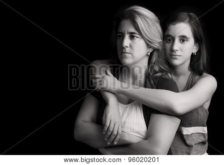 Emotional black and white portrait of a sad and angry mother with her teen daughter embracing her