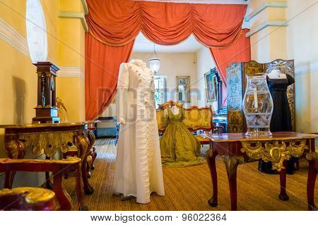 Living room decorated  with wooden tables including gold painted details, yellow carpet and a female