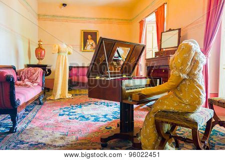 Living room decorated in wooden tables including gold painted details, yellow carpet with a female d
