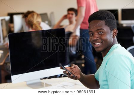 Male College Student Using Mobile Phone In Classroom