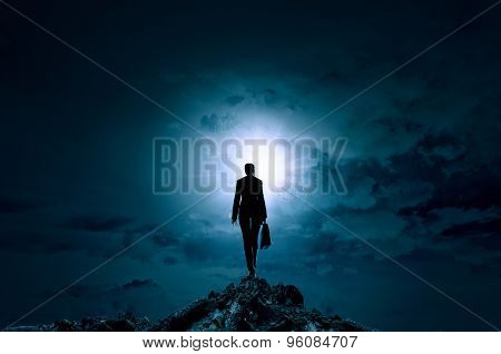 Rear view of businesswoman standing on top and looking in sky