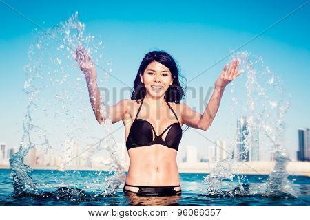 Woman on city beach splashing water drops