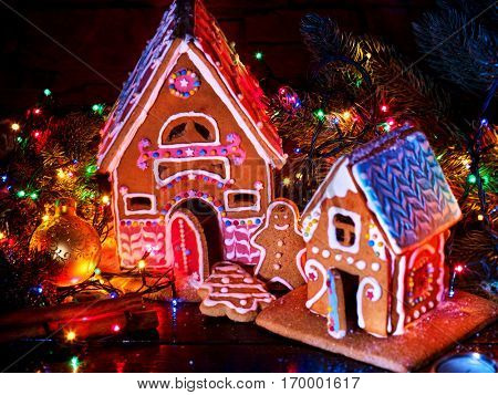 Gingerbread houses country with christmas lights string on wooden table. Close up Xmas cookies decorating christmas ball and tree. Light effect for festive dinner. Nobody on night picture