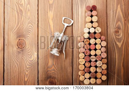 Wine bottle shaped corks and corkscrew over rustic wooden table background. Top view with copy space