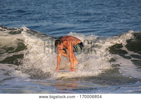A young man in his early 20's surfing. He has caught a wave in the Atlantic Ocean. The location is the New Jersey Shore.