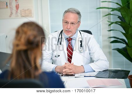Senior doctor listening to a patient in his studio